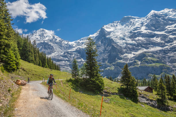mountain biking in Switzerland nice and ever young senior woman riding her e-mountainbike below the Eiger northface, Jungfrauregion, jungfrau region stock pictures, royalty-free photos & images