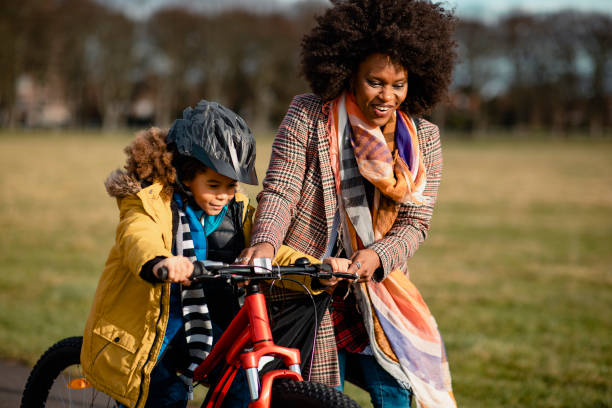 aprendiendo a andar en bicicleta - togetherness learning playful mother fotografías e imágenes de stock