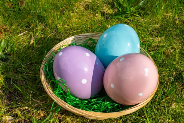 Colorful ceramic easter eggs in a basket on a meadow.
