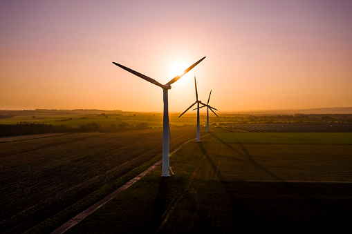 Three large wind turbines at sunrise taken from the air