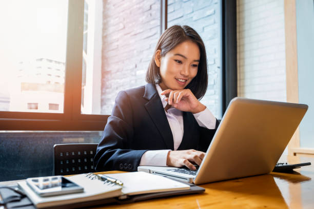 zbliżenie bizneswoman za pomocą laptopa w biurku. przeszukuje informacje o internecie lub przeglądanie. - asian ethnicity women young adult cheerful zdjęcia i obrazy z banku zdjęć