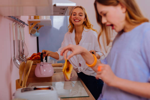 istock Older sister laughing while watching her sister touching hot toast 1139941328