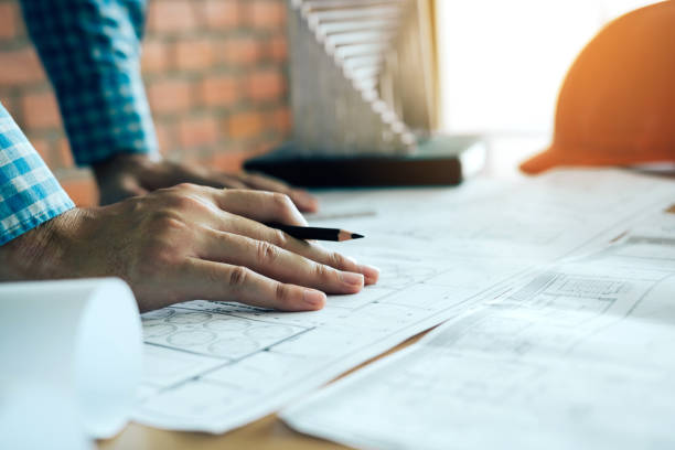 istock Hand of young engineering man drawing on blueprint with model on desk. 1139942393