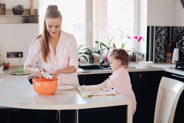 istock Little lovely kid helping parent with dough at kitchen. 1139942695