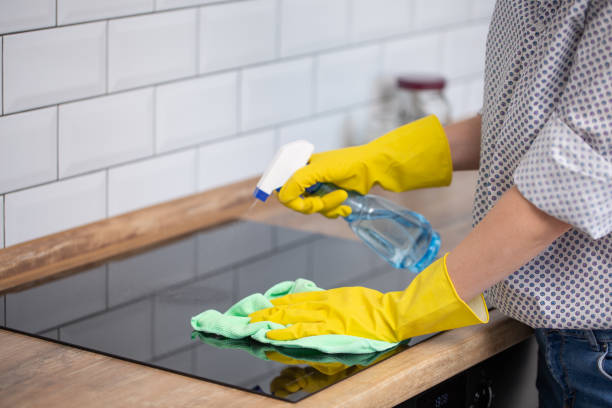 Close up of human hand with protective gloves cleaning induction hob with rag and holding spray bottle. Close up of human hand with protective gloves cleaning induction hob with rag and holding spray bottle. Homework cleaning stove domestic kitchen human hand stock pictures, royalty-free photos & images