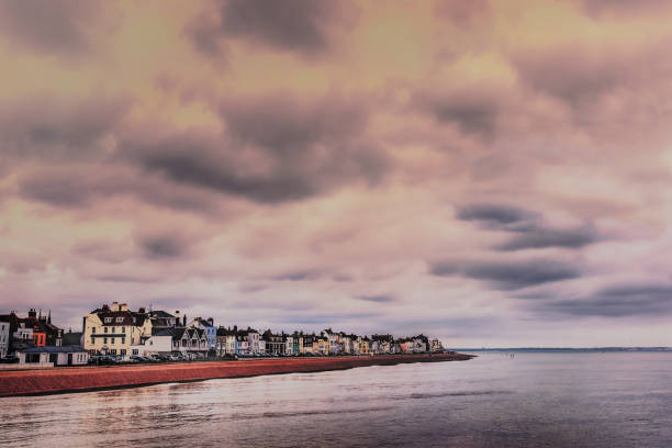 vista ao longo dos edifícios bonitos e do litoral de deal, kent, reino unido como visto do cais em um dia de inverno nebuloso com um mar de prata e reflexões. - pebble water gray silver - fotografias e filmes do acervo