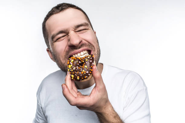 Big guy is starving. He decided to eat tasty small fat donut covered with chocolate. He is biting it with delisions feeling and pleasure. Isolated on white background. Big guy is starving. He decided to eat tasty small fat donut covered with chocolate. He is biting it with delisions feeling and pleasure. Isolated on white background chocolate fingers stock pictures, royalty-free photos & images