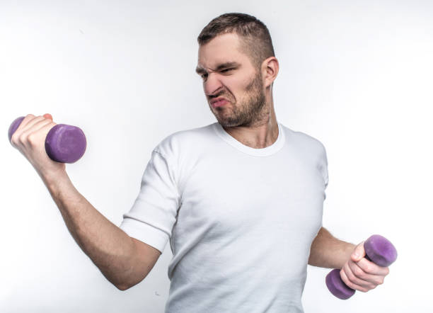 istock Thin guy is holding dumbbells in his hands. He is trying to gain some muscles before summers will come. He wants to start to go to fitness club. Isolated on white background. 1139946044