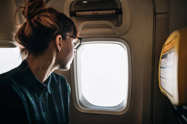 istock Young Traveler Woman Looking through Airplane Window 1139947663