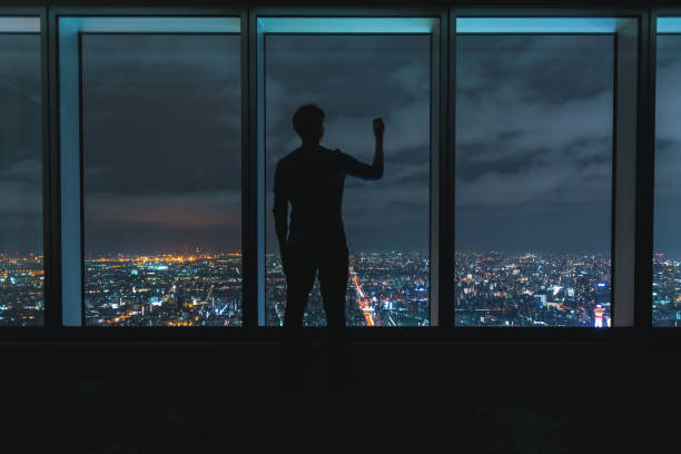 istock Man writing on large windows high above a sprawling city 1139948386