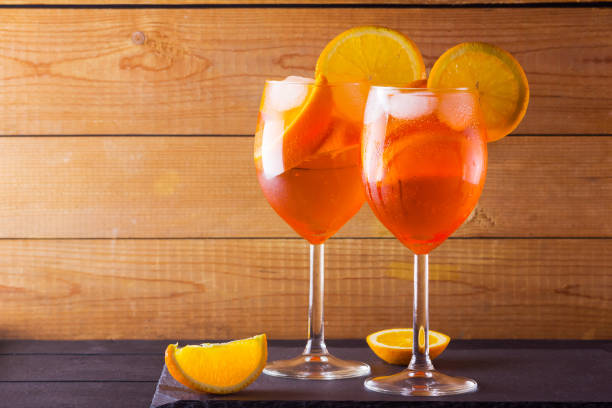 Cocktail Spritz on wooden boards. Two glasses with summer alcoholic cocktail with orange slices. Italian cocktail Spritz on wooden background