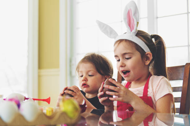 sister and brother eating chocolate - child easter egg home improvement easter imagens e fotografias de stock