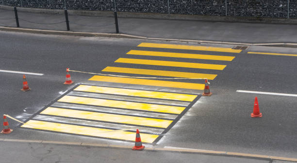 freshly painted pedestrian crosswalk cordoned off freshly painted pedestrian road crosswalk with bright yellow paint for road and traffic safety in a Swiss village freshly painted road markings stock pictures, royalty-free photos & images