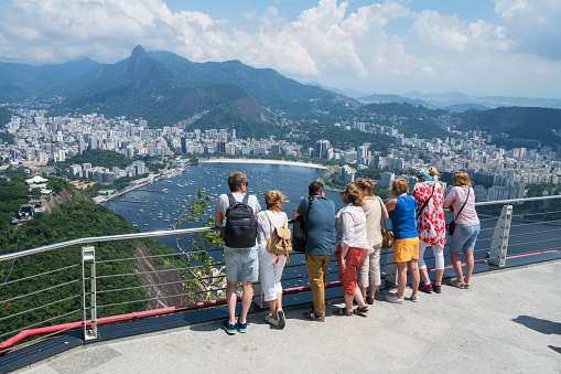 Rio de Janeiro, Brazil - March 10, 2019:  Tourists on a observation area on the Sugarloaf Mountain enjoying the view towards Botafogo bay and Corovado Mountain