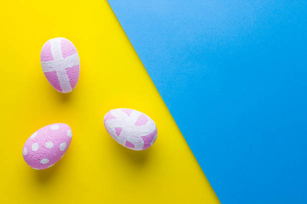 istock Pink Easter eggs on a yellow blue background. Easter minimal concept. Eggs with an ornament on a multicolored background. Flat lay 1139960279