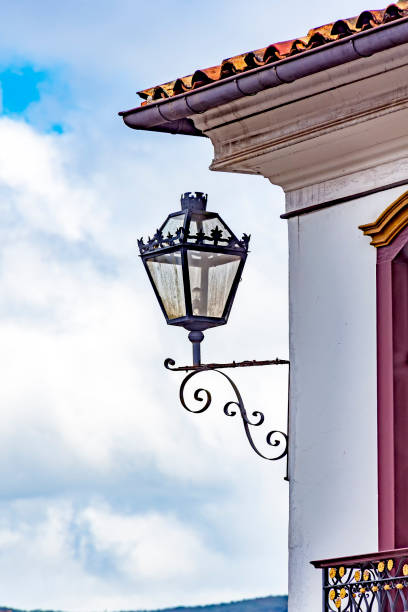 Old residential lighting lantern next to a window of an old colonial architecture building in the city of Ouro Preto in Minas Gerais
