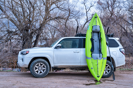 Fort Collins, CO, USA - April 1,  2019 : Toyota 4 Runner SUV (2016 Trail Edition) with a whitewater inflatable kayak (Aire Force) at dusk after paddling on the Poudre River, early spring scenery.