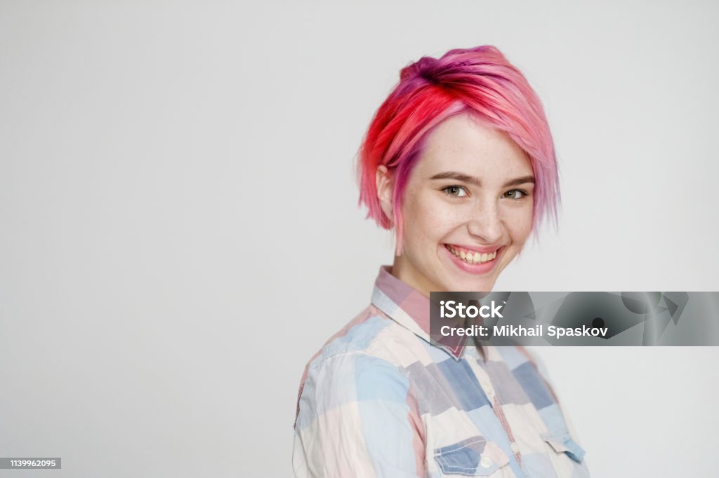 Junges schönes Mädchen mit einem kurzen Haar geschnitten Pixie-Bob. Farbhaarkolbung, rot rosa Farbe. Shirt im Keller, lässiger Stil. - Lizenzfrei Haar Stock-Foto
