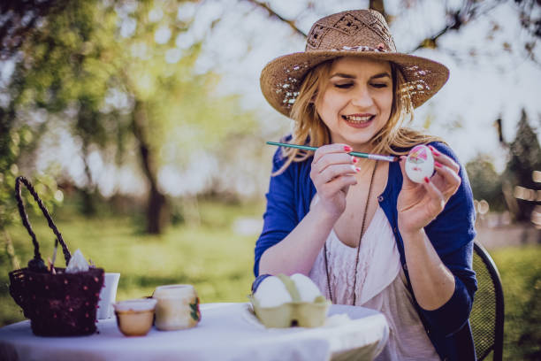 istock Young woman decorating Easter eggs to celebrate holiday 1139963269