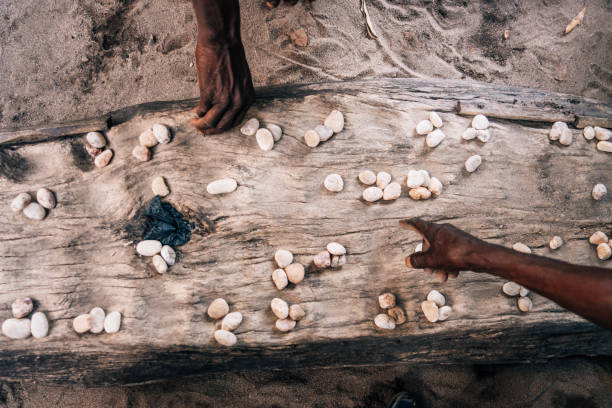 die hände spielen mancala-spiel, das in afrika sehr beliebt ist - thumb stones stock-fotos und bilder