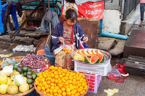 Woman selling cut fruits at the streets of Yangon (Rangoon), Myanmar (Burma). January 2019