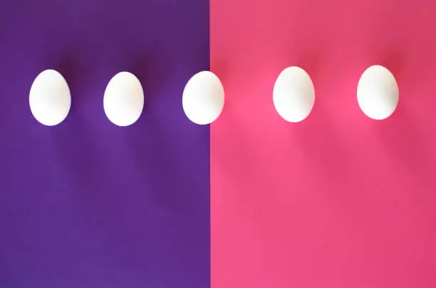 Five easter white eggs on a purple-pink background.