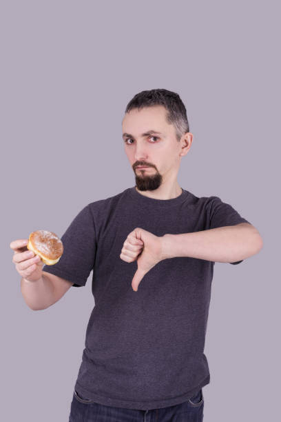 istock Man with a beard eating a bun over gray background 1139974615