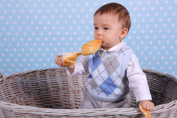 istock A tiny child eats a dry bun in a basket woven from a wicker tree. 1139978456