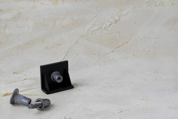 Two metal pop Rivet fasteners, one in black plastic detail to connect on grey cement background. Horizontal with copy space for text and design. Ingeneering. Two metal pop Rivet fasteners, one in black plastic detail to connect on grey cement background. Horizontal with copy space for text or design. Ingeneering. riveting stock pictures, royalty-free photos & images