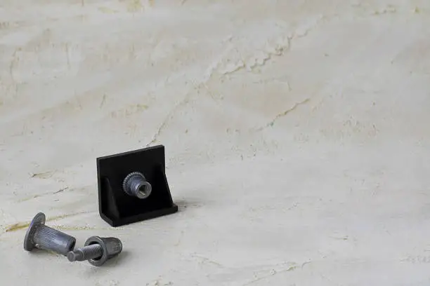 Photo of Two metal pop Rivet fasteners, one in black plastic detail to connect on grey cement background. Horizontal with copy space for text and design. Ingeneering.