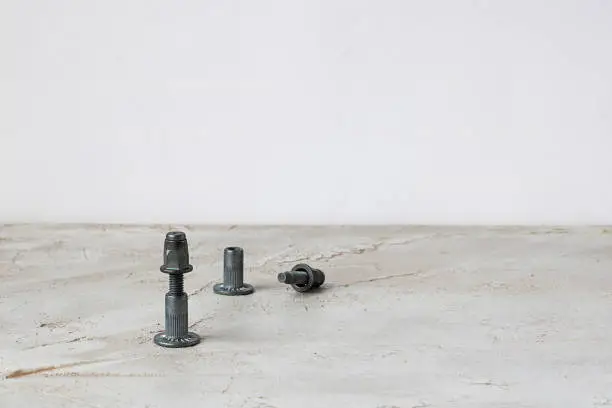 Photo of Two metal pop Rivet fasteners, one is joined on grey cement background. Horizontal with copy space for text and design. Ingeneering.