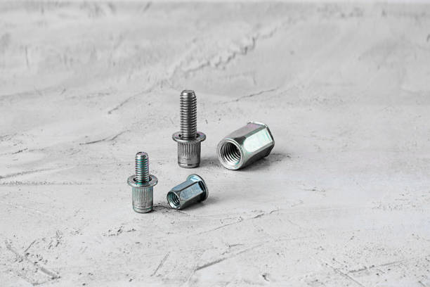 two metal pop rivet fasteners of different size, on grey cement background. horizontal with copy space for text and design. ingeneering. - screw human head bolt isolated imagens e fotografias de stock