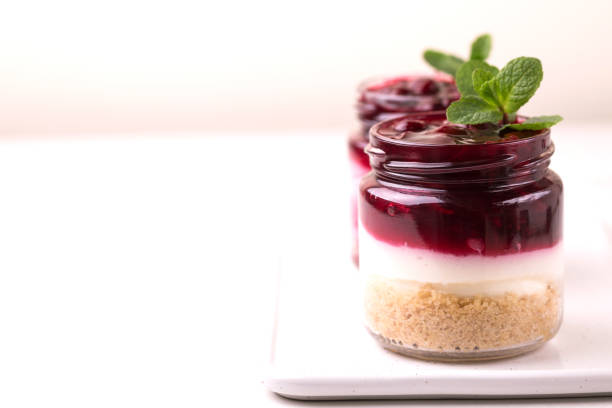 Layered cherry bisquit dessert with ricotta, mint and honey in glass jar. Yogurt cheesecake breakfast