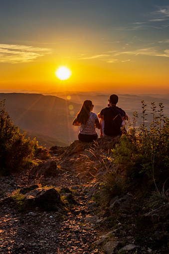 A young couple watching the beautiful summer sunset from Kopitoto Hill, Vitosha Mountain, Sofia, Bulgaria