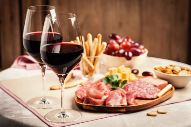 Red wine with charcuterie and cheese Two glasses of red wine with charcuterie, cheese, grapes and snacks beaujolais stock pictures, royalty-free photos & images