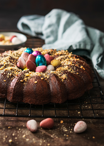 Rustic Easter cake with chocolate and colourful Easter eggs on dark background. Top view. Selective focus. Copy space.