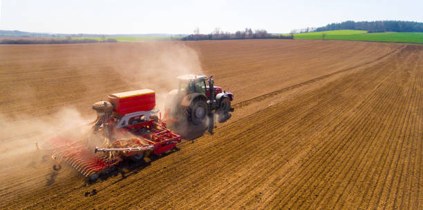aerial view to a tractor with sowing machine working on a  field. agriculture from above. - tractor agricultural machinery agriculture commercial land vehicle imagens e fotografias de stock
