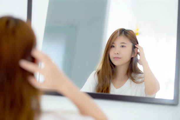 beautiful of portrait asian young woman examining with face and smile looking on mirror at bedroom, girl beauty of makeup and dressed up with reflection, lifestyle and wellness concept. - mirror women looking reflection imagens e fotografias de stock