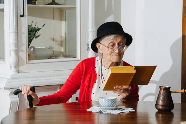 istock Kind grandmother is reading her book at dinner table at home. 1139998148