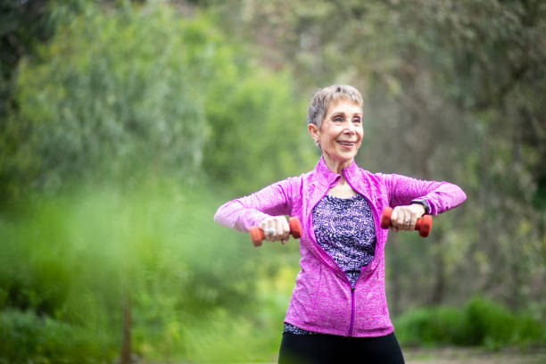 istock Senior Woman Lifting Weights in Forest 1139999620