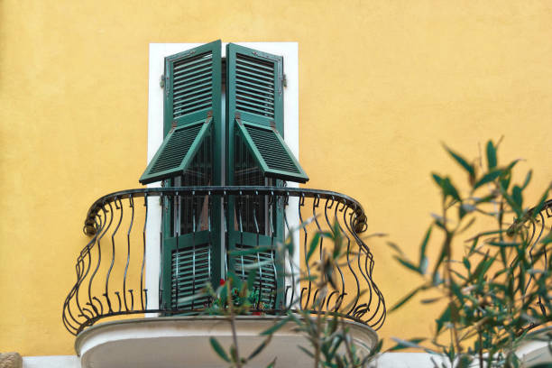 istock metallic black balcony with green wooden doors with shutters in white frame on yellow wall 1140001359