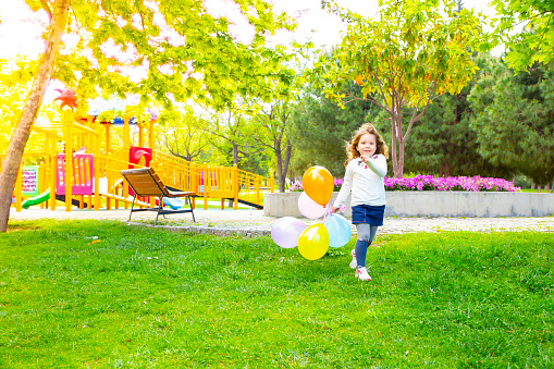 Happy kid girl playing with colorful bunch of balloons