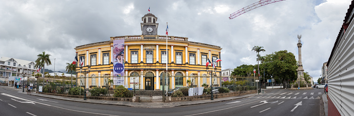 Saint Denis, Reunion Island - January 26th, 2019: Panoramic view of the city hall building (\nHôtel de Ville de Saint-Denis) next to the War memorial monument (Monument aux Morts) in Saint Denis, Reunion.