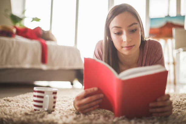 istock Girl reading a book, lying down on the floor 1140015612