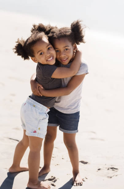 Loving siblings Shot of two beautiful little girls embracing on the beach beauty in nature vertical africa southern africa stock pictures, royalty-free photos & images