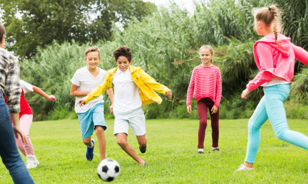 istock Kids playing football in park 1140018696