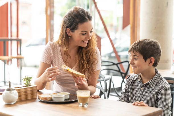 istock Beautiful mother and son talking while she spreads butter on toast both smiling 1140018863