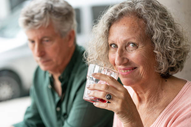 istock Beautiful elder woman on a date enjoying a cold drink while facing camera smiling 1140019412