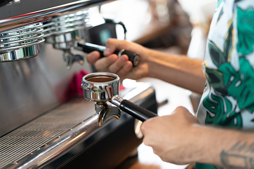 Close up of unrecognizable male barista making coffee with a machine