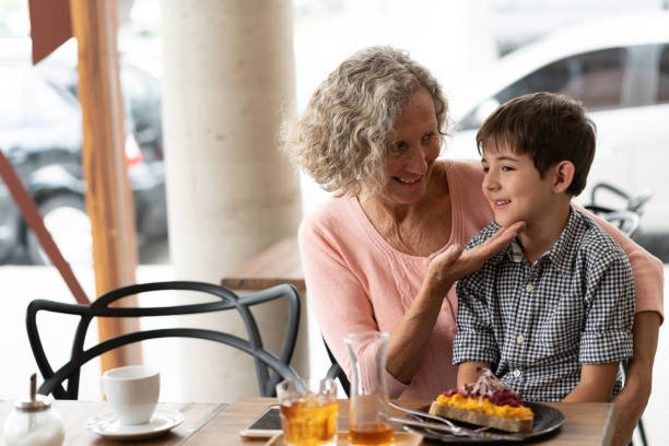 Loving grandmother caressing grandson while he sits on her lap at the restaurant